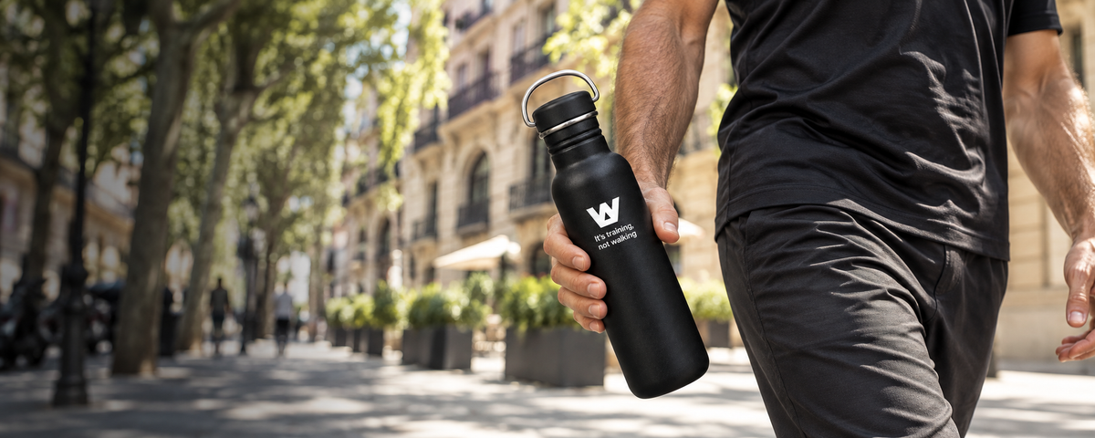 Botella WalkBCN en la mano mientras camina por Barcelona, sin mostrar el rostro.