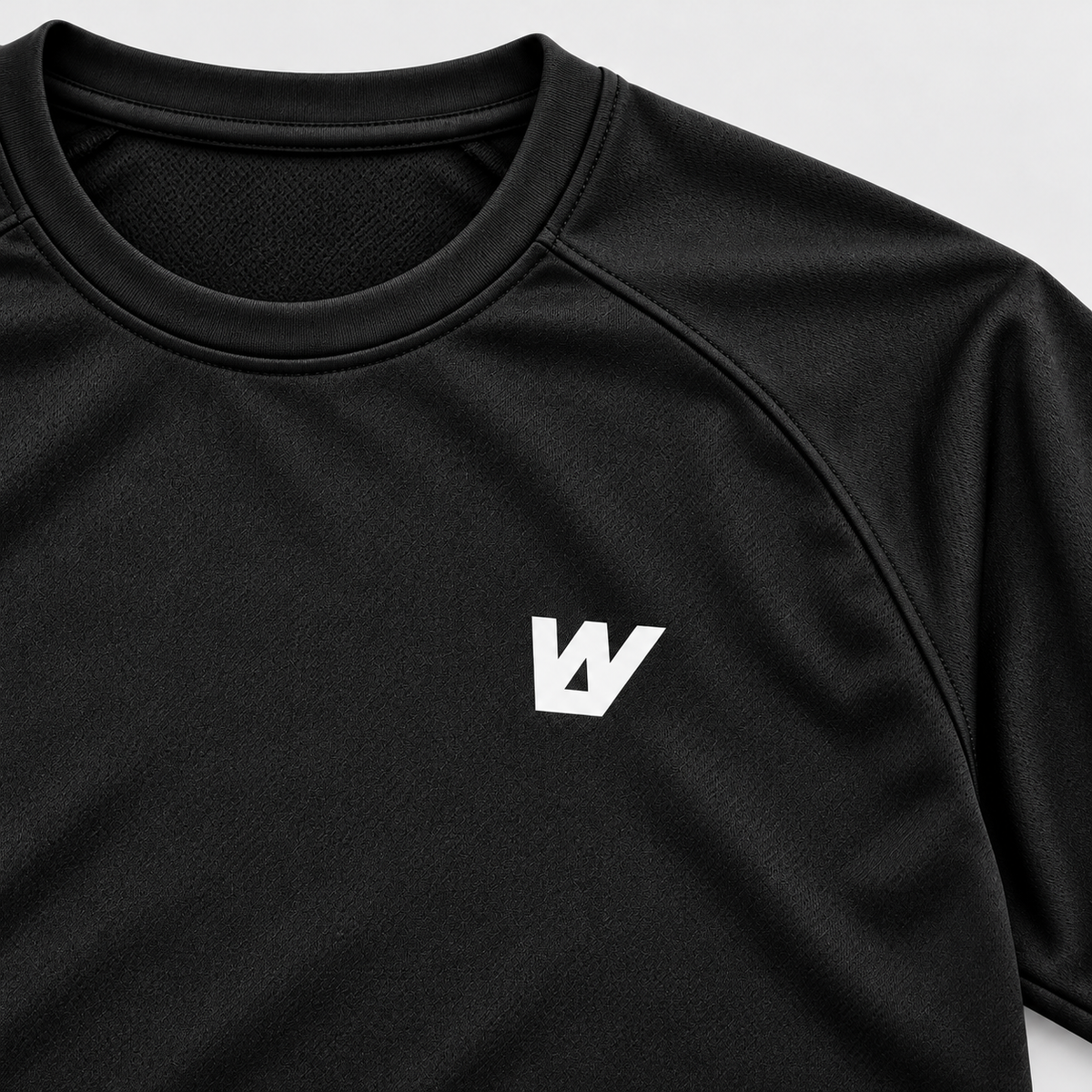 Detalle del logo W blanco en el pecho y el tejido negro de la camiseta WalkBCN. Mockup.